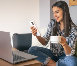 Woman viewing laptop and making a call on her mobile phone